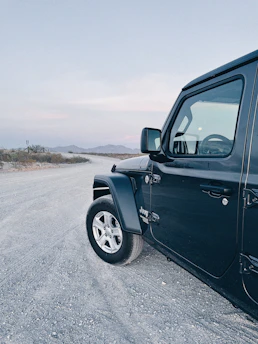 Robust black heavy-duty truck parked on a gravel road with mountains in the background.