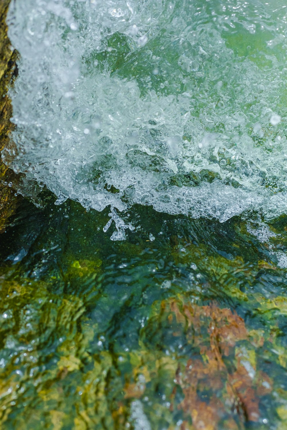 a close up of a wave coming over a rock