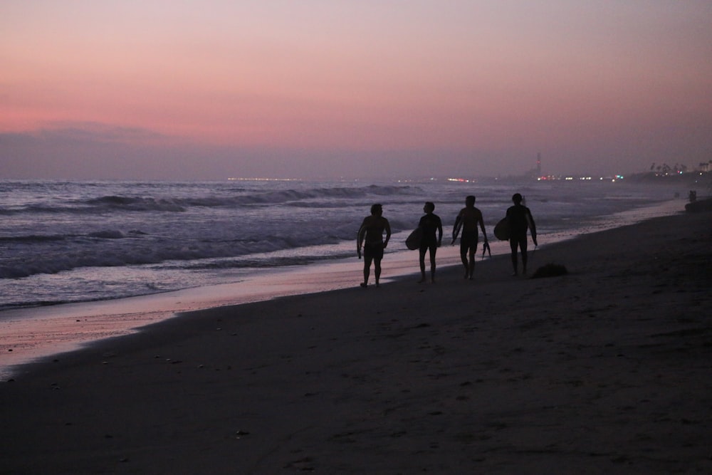 a group of people walking along a beach next to the ocean