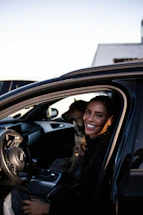 a woman sitting in a car with a dog