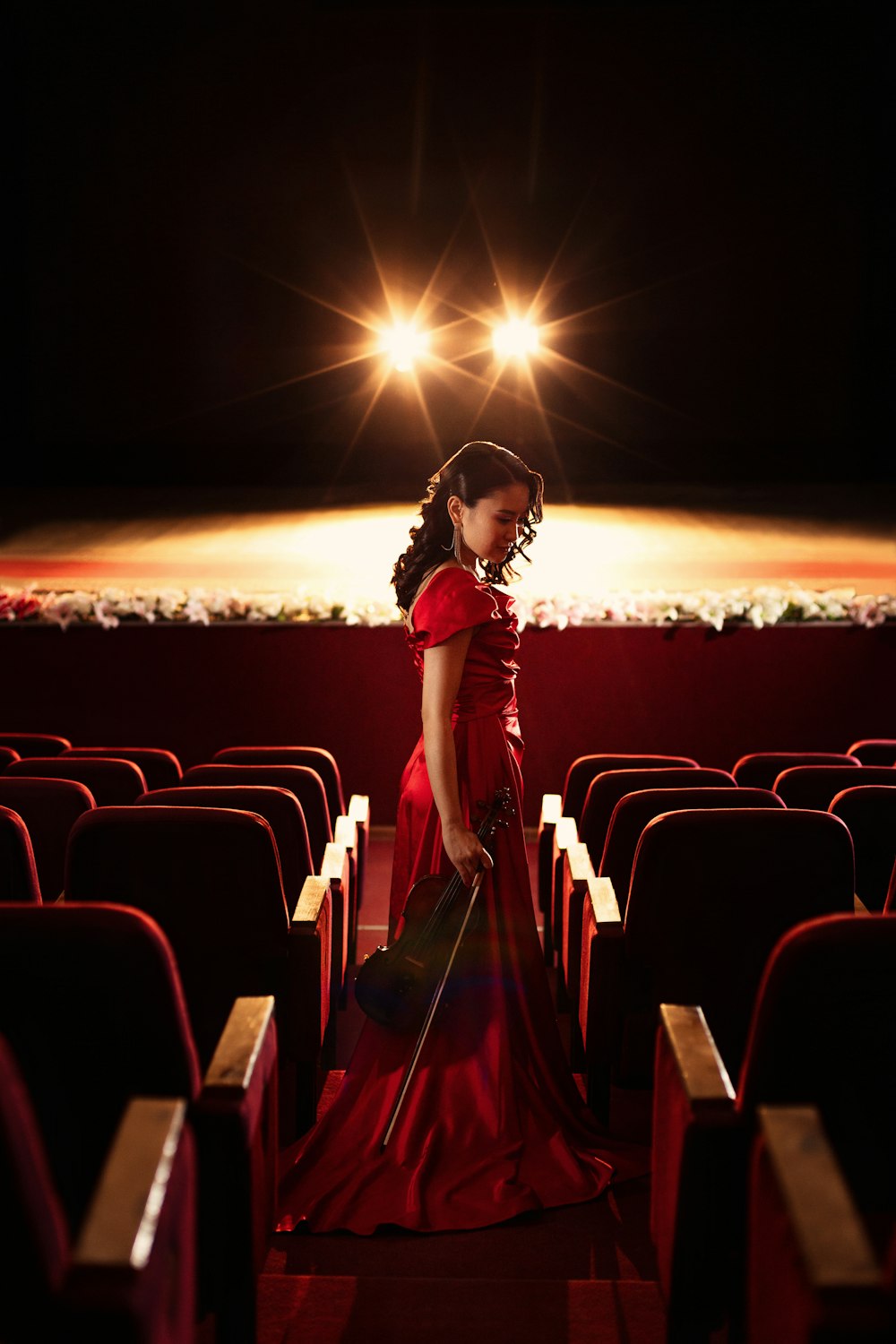a woman in a red dress standing in a theater