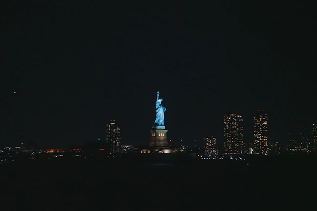 Nighttime shot of the Statue of Liberty illuminated against a dark sky, symbolizing resilience.