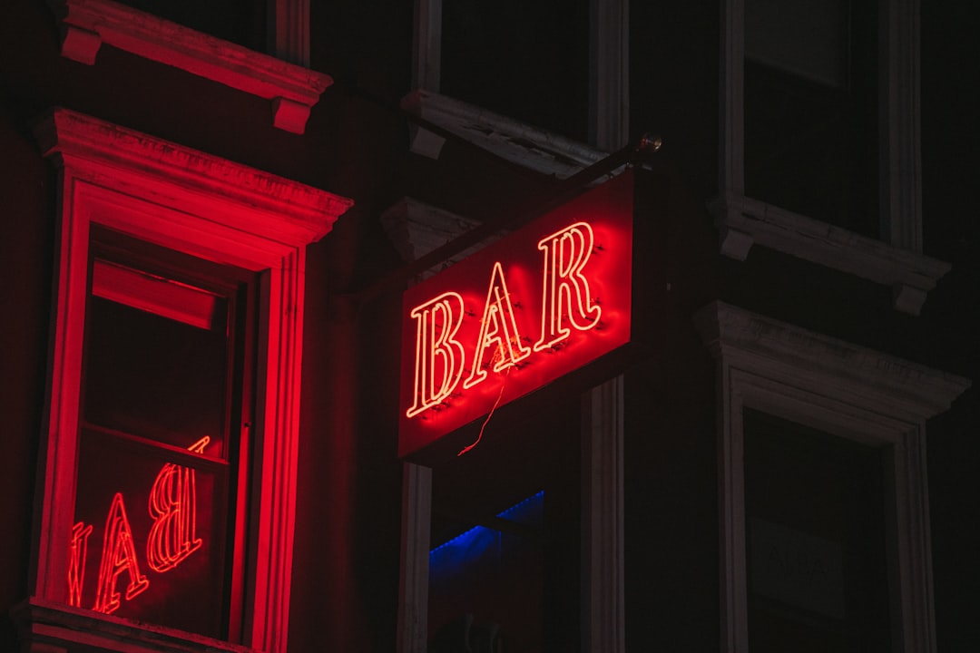 a red bar sign lit up in the dark,