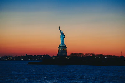 The Statue of Liberty glowing softly at sunset, symbolizing hope and new beginnings.