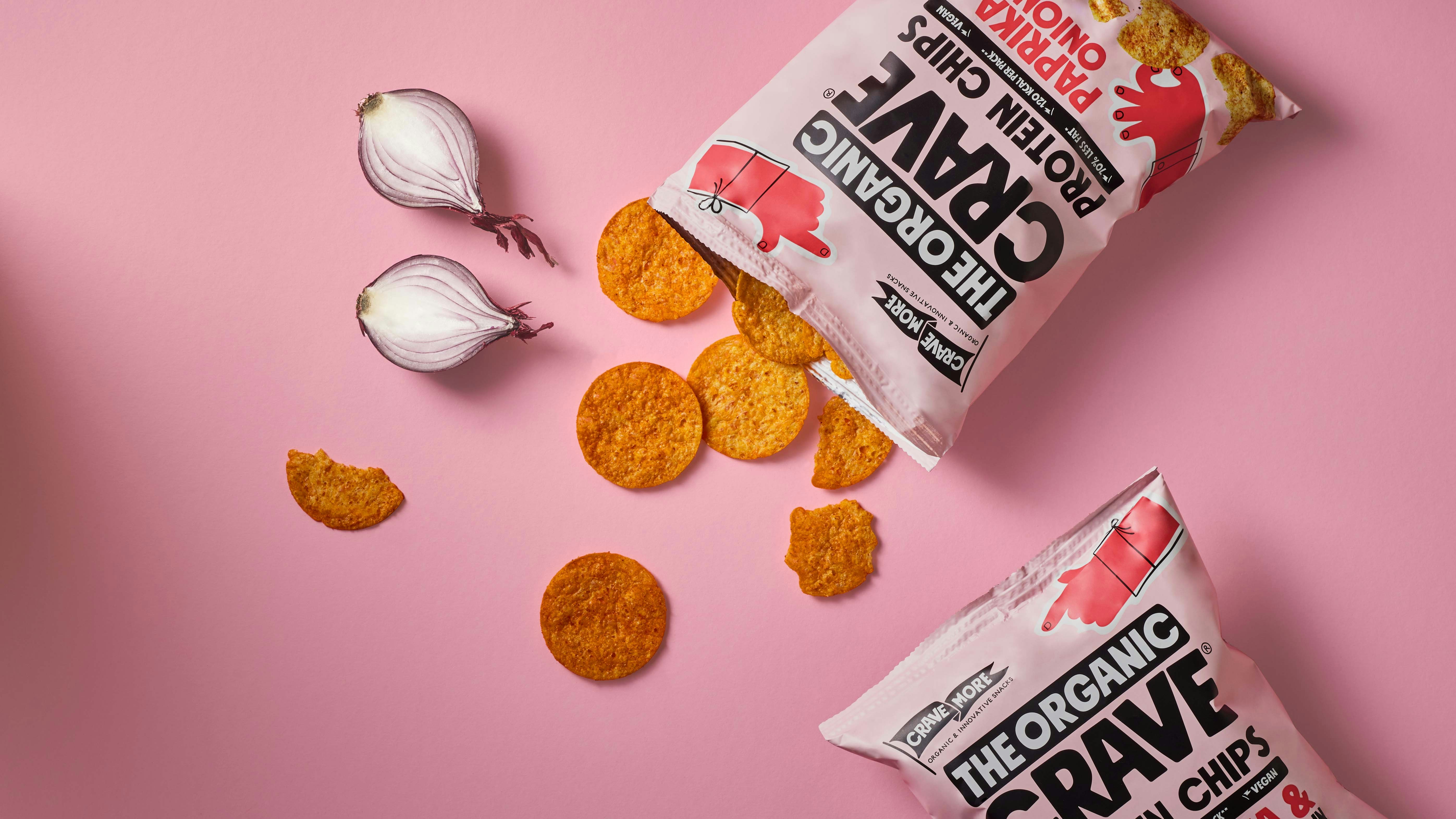 Una bolsa de galletas junto al ajo sobre un fondo rosado