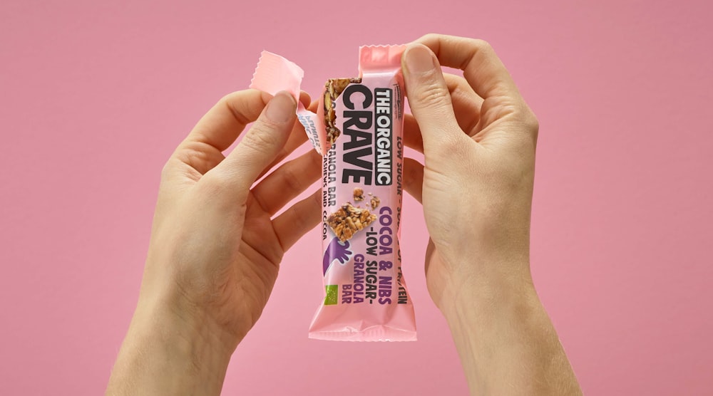 a person holding up a pink bar of candy