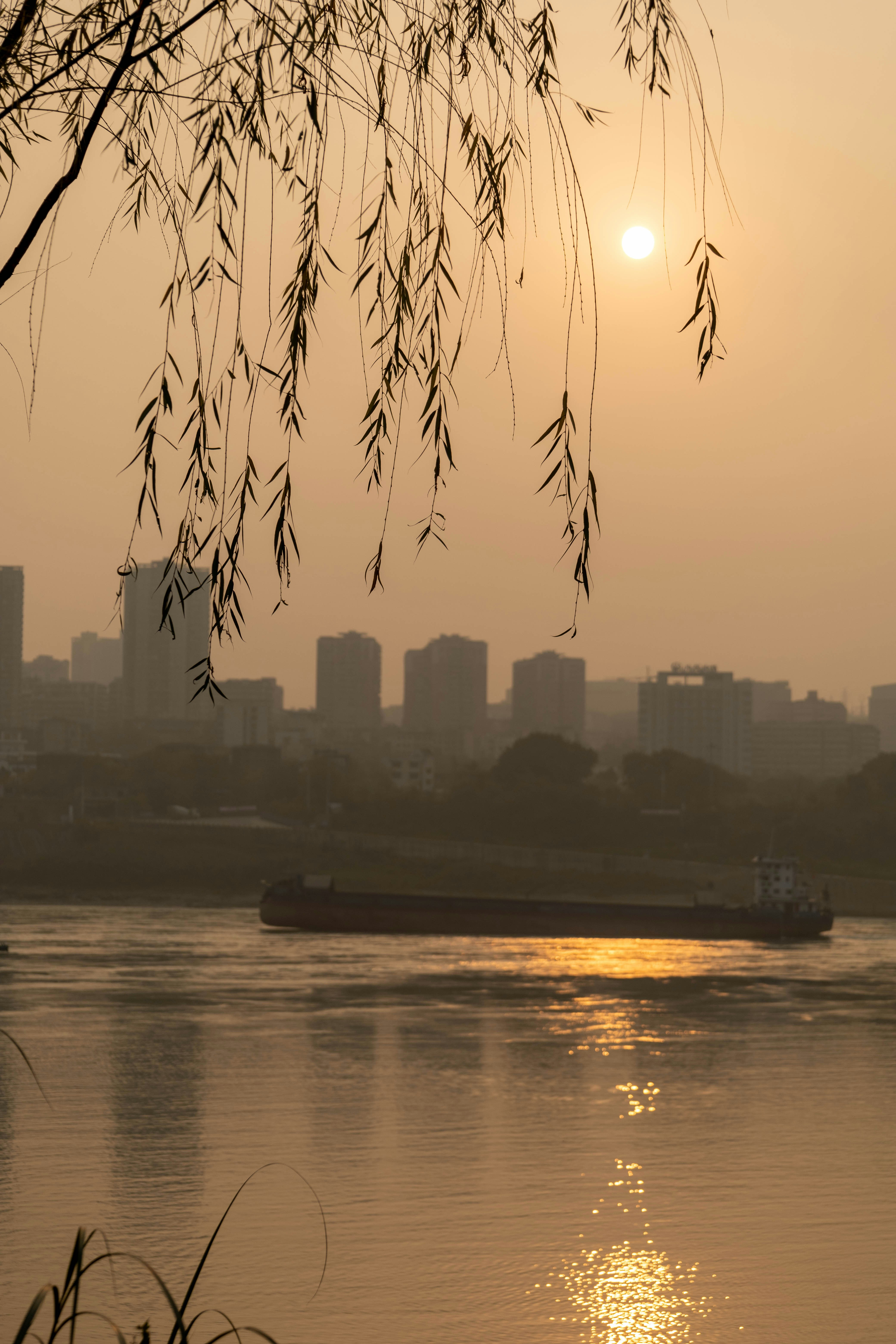 the sun is setting over the water and a boat is in the water