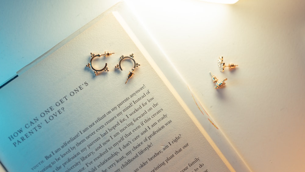a book with a pair of earrings laying on top of it
