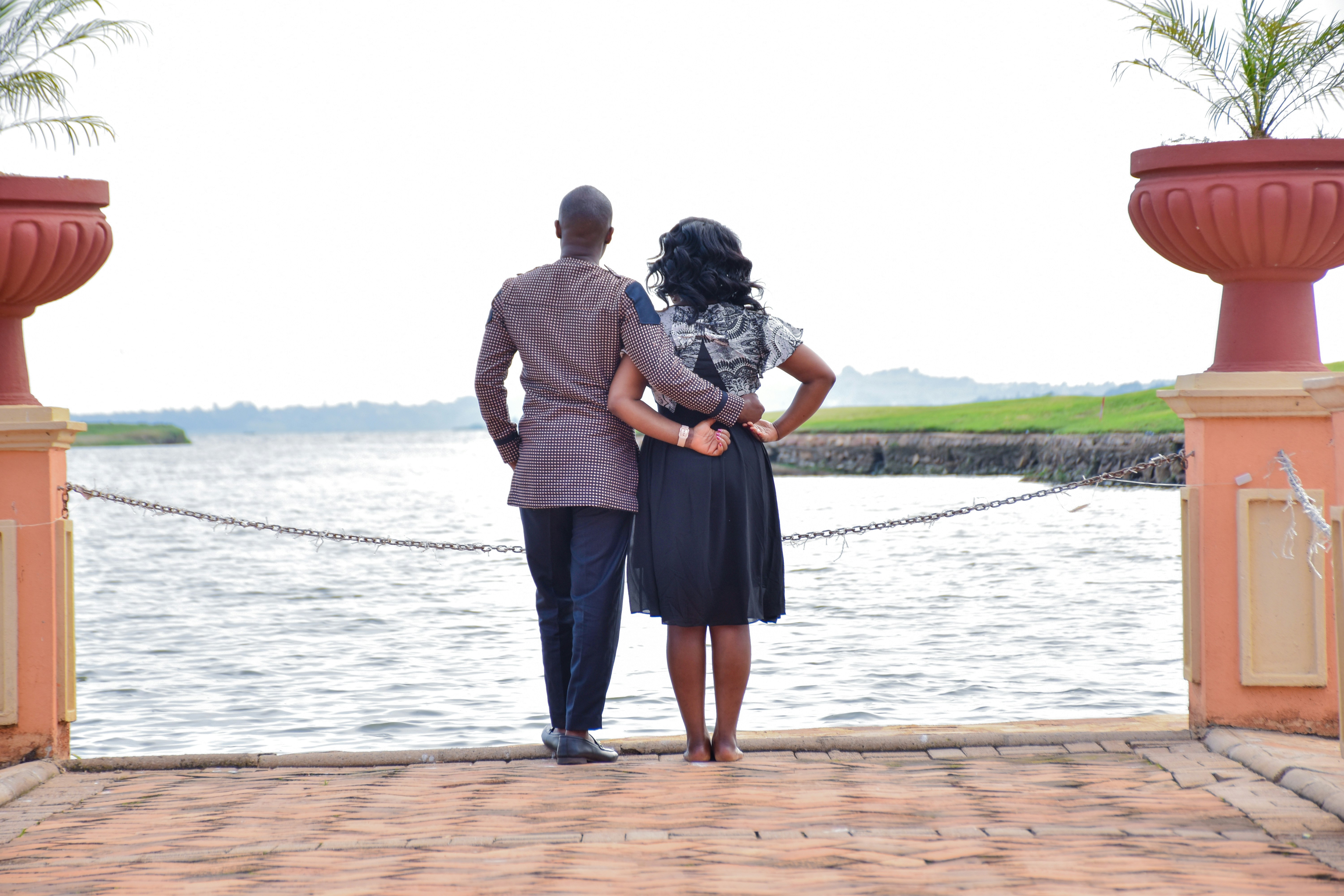 a man and a woman standing on a dock next to a body of water