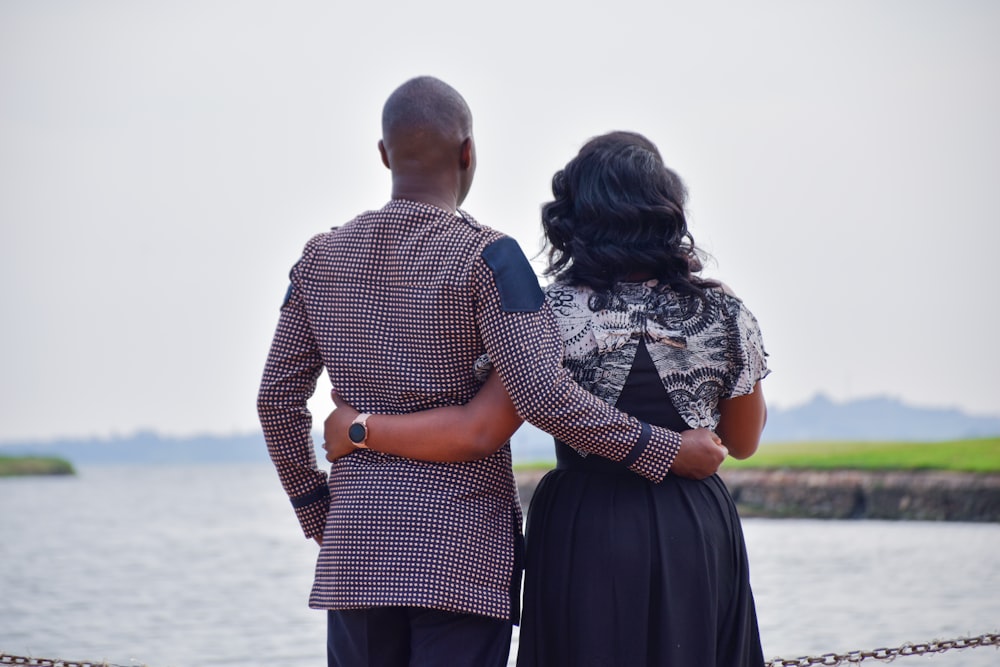 a man and a woman standing next to a body of water