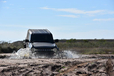 a black truck driving through a muddy field
