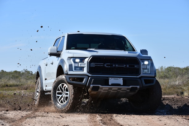 a white truck is driving through the mud