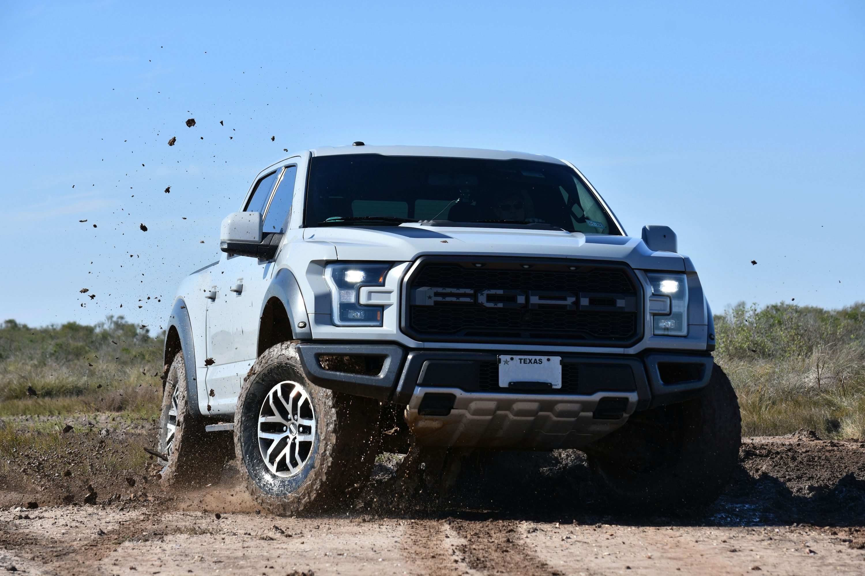 a white truck is driving through the mud