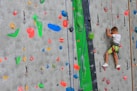 a young boy climbing up the side of a climbing wall
