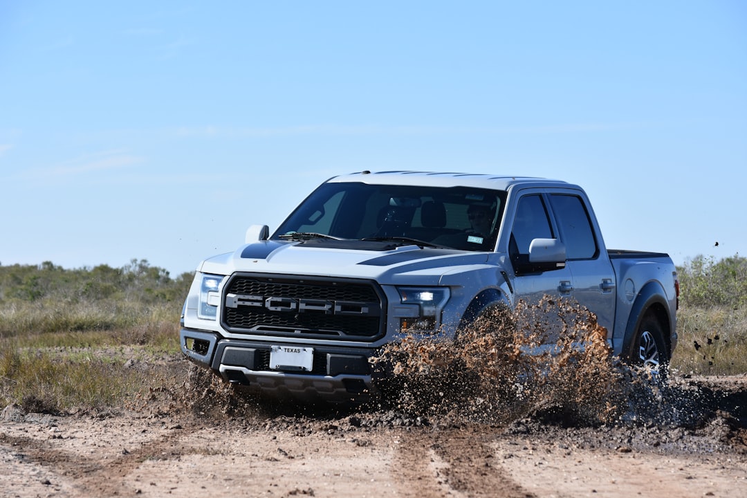 a silver truck is driving through the mud,
