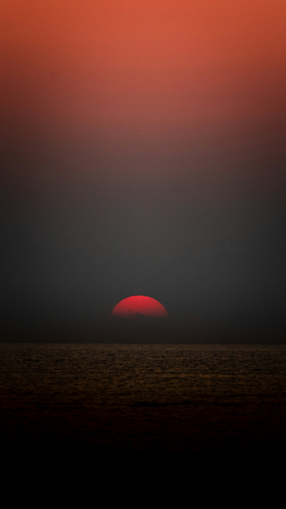 the sun is setting over the horizon of the ocean