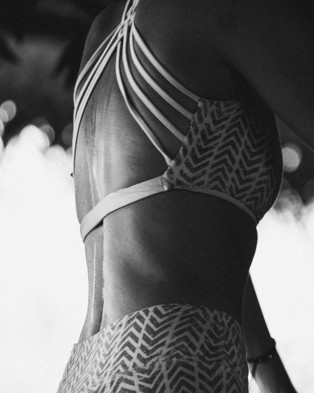a black and white photo of a woman in a bikini top