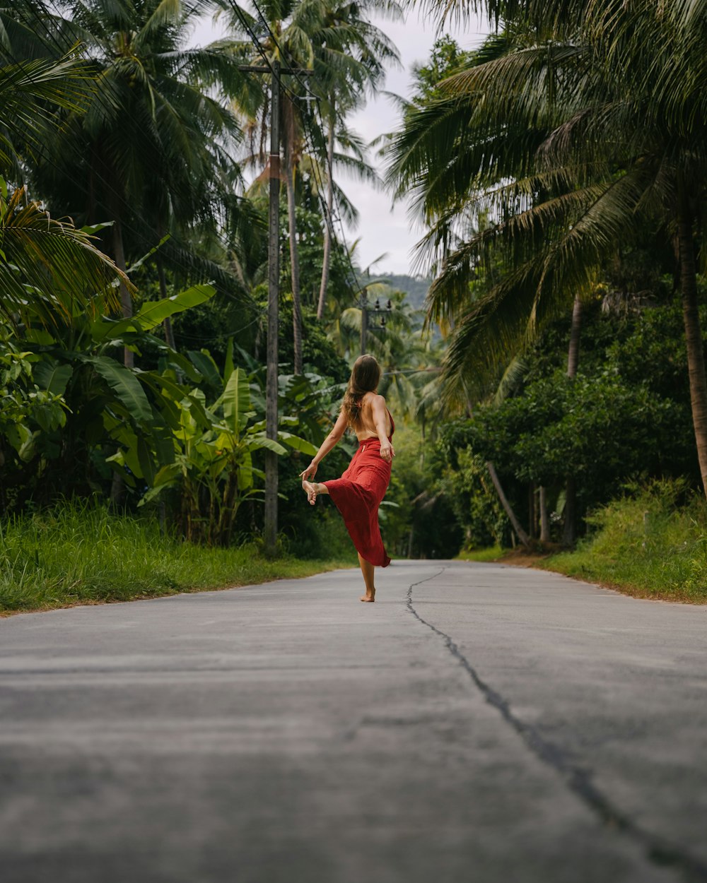 a woman in a red dress is running down the road