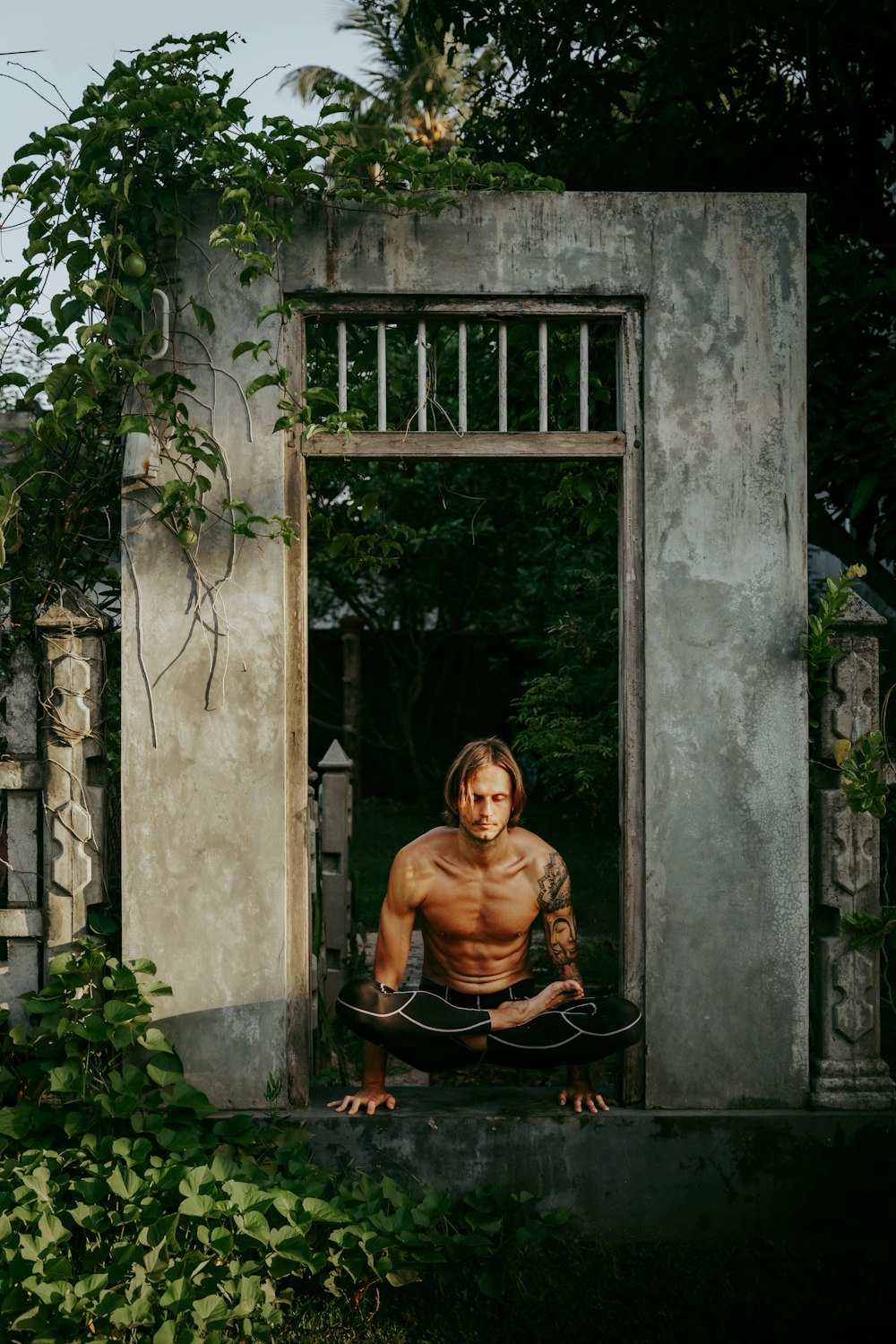 a shirtless man sitting in a doorway with a skateboard