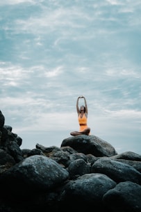 a woman is doing yoga on a rock