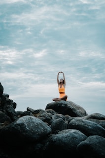 a woman is doing yoga on a rock