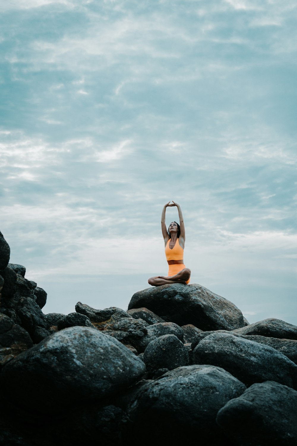 a woman is doing yoga on a rock