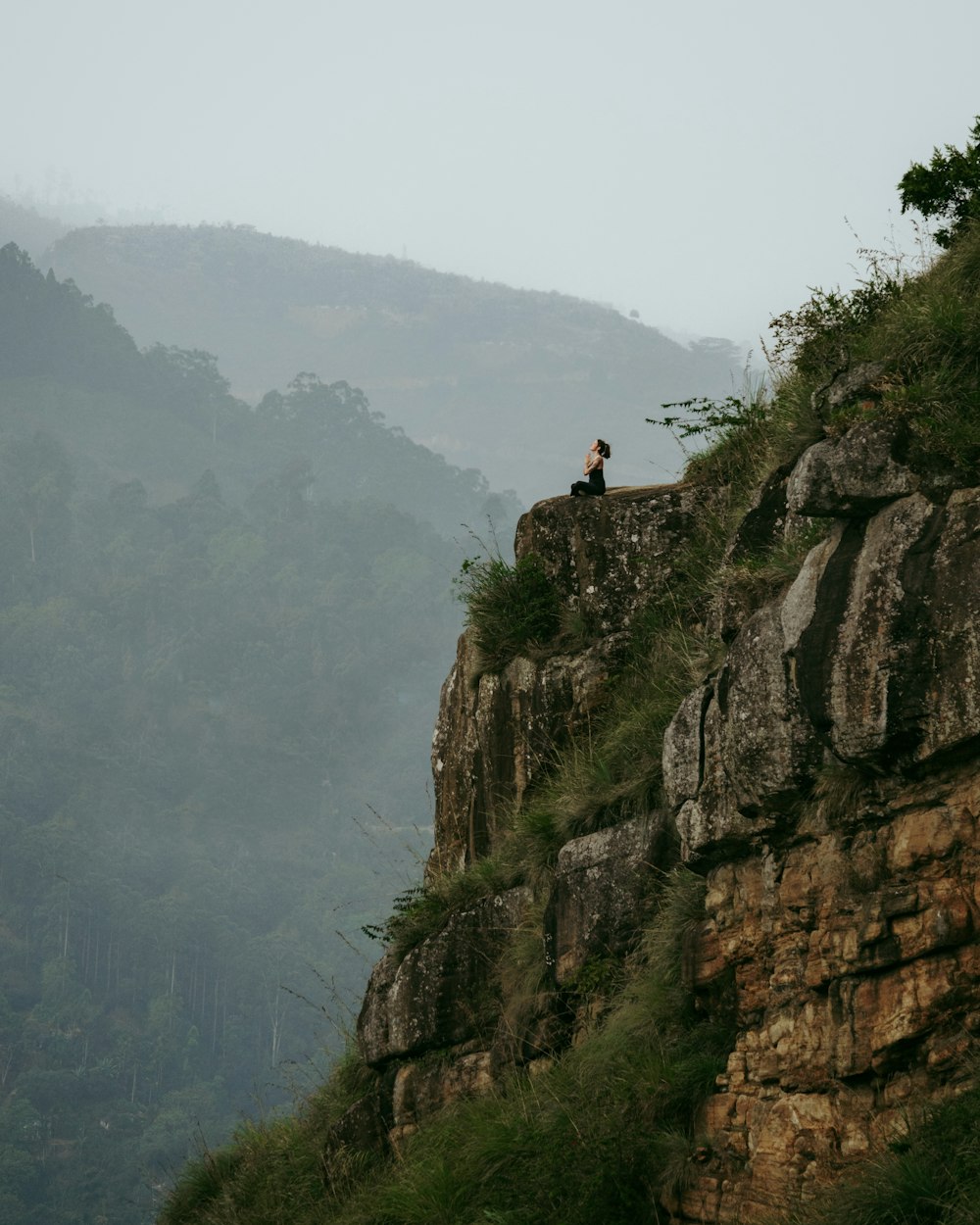 a person sitting on top of a cliff