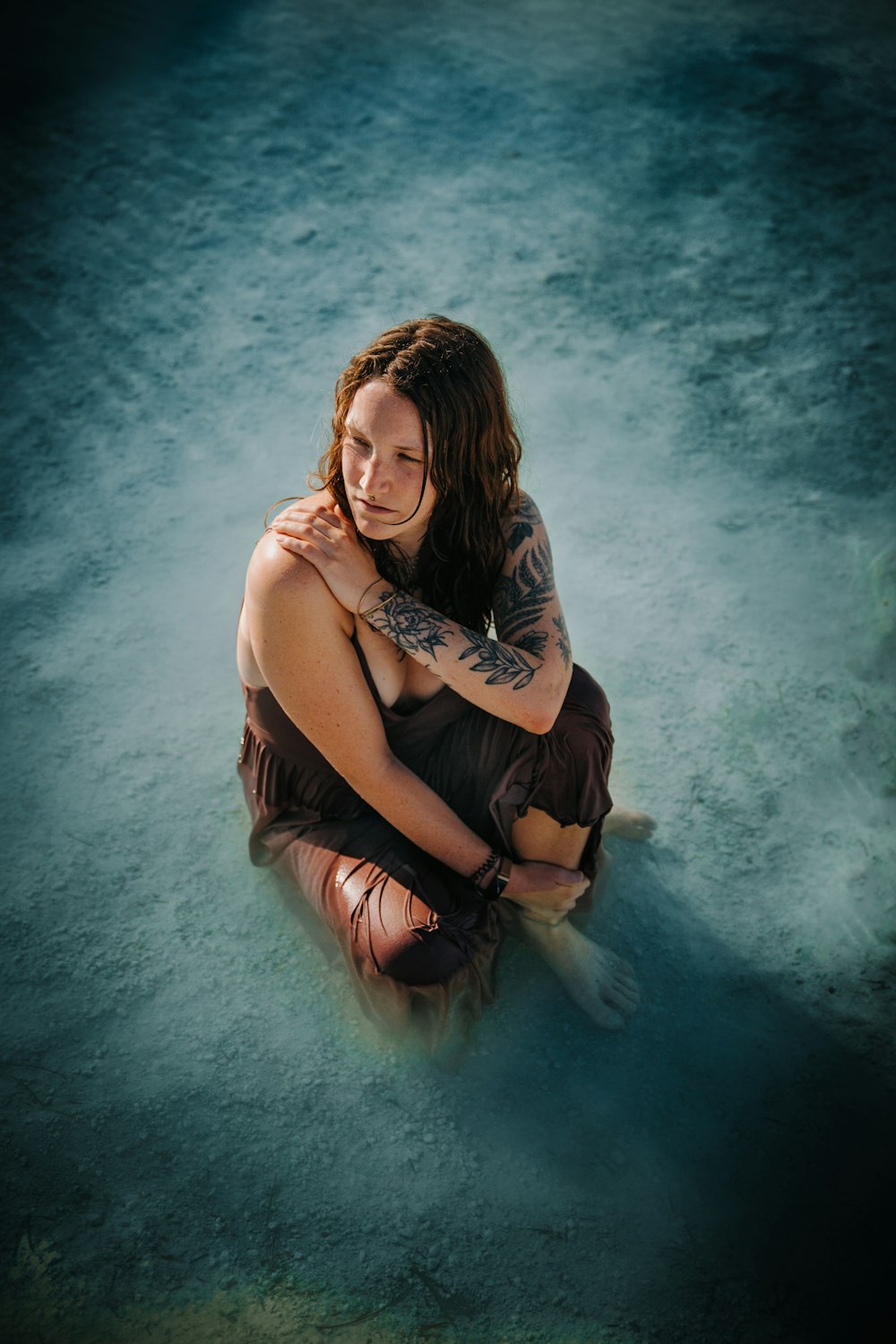 a woman sitting on the ground with a tattoo on her arm