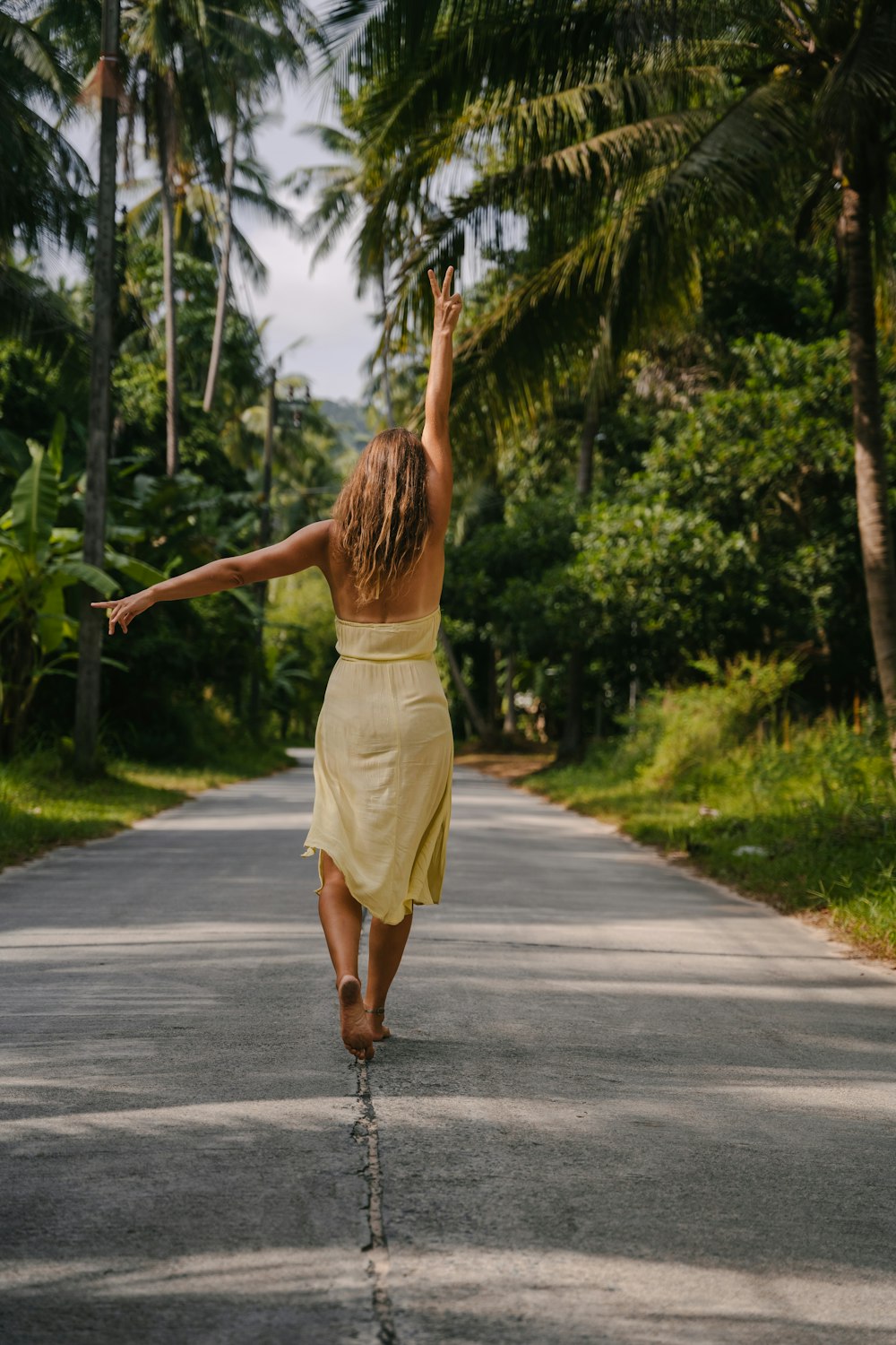 a woman in a yellow dress walking down a road