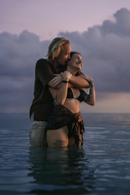 A couple sharing a joyful moment splash in water at sunset.