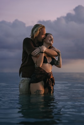 A couple sharing a joyful moment splash in water at sunset.