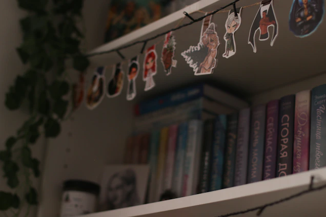 A sleek erdvėja bookshelf standing in a sunlit living room corner, filled with books and small plants.