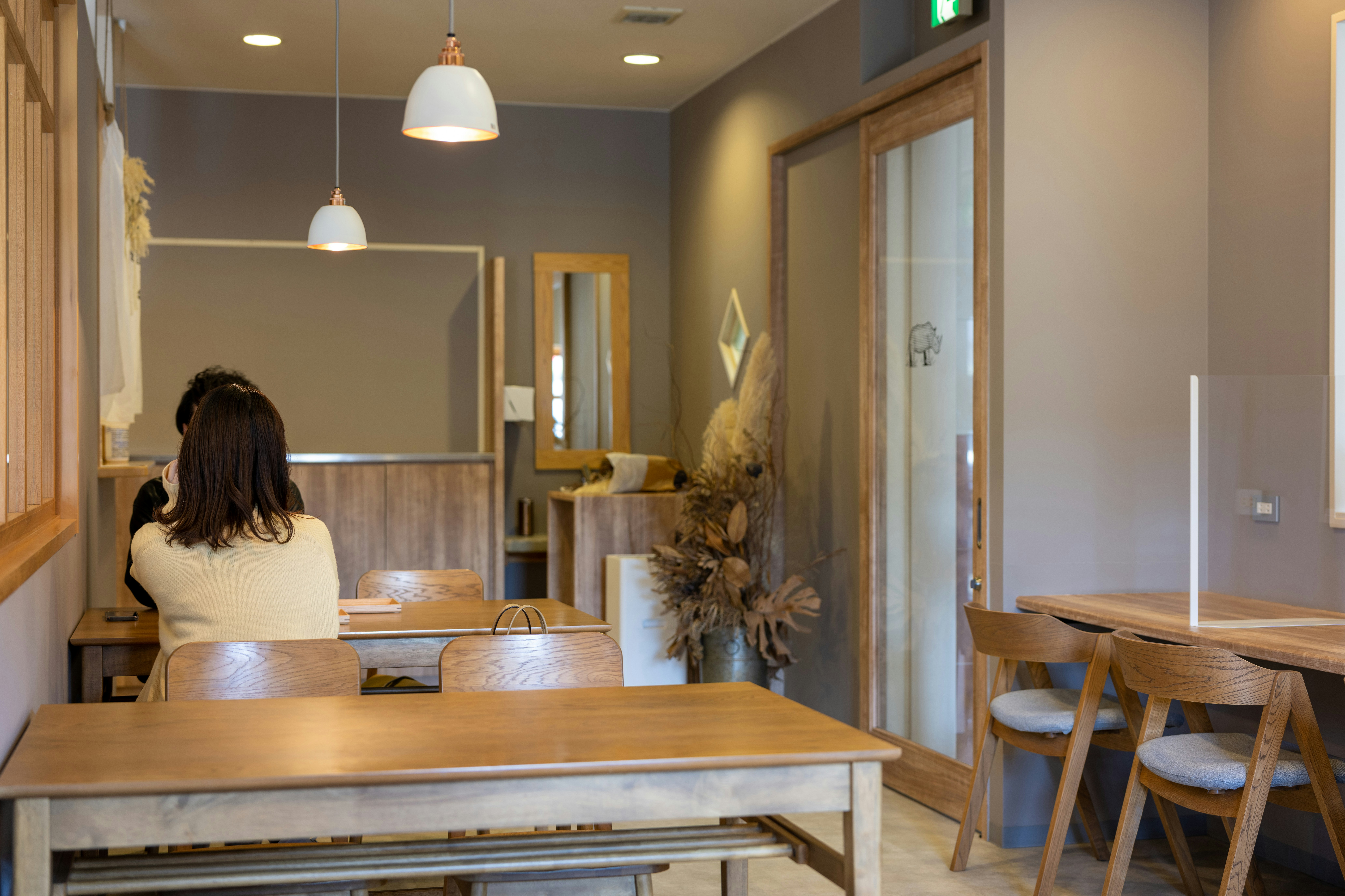 Warm café interior with golden lighting and guests enjoying coffee at wooden tables