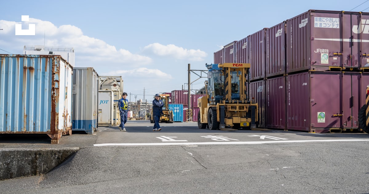 A man walking down a street next to lots of shipping containers photo ...