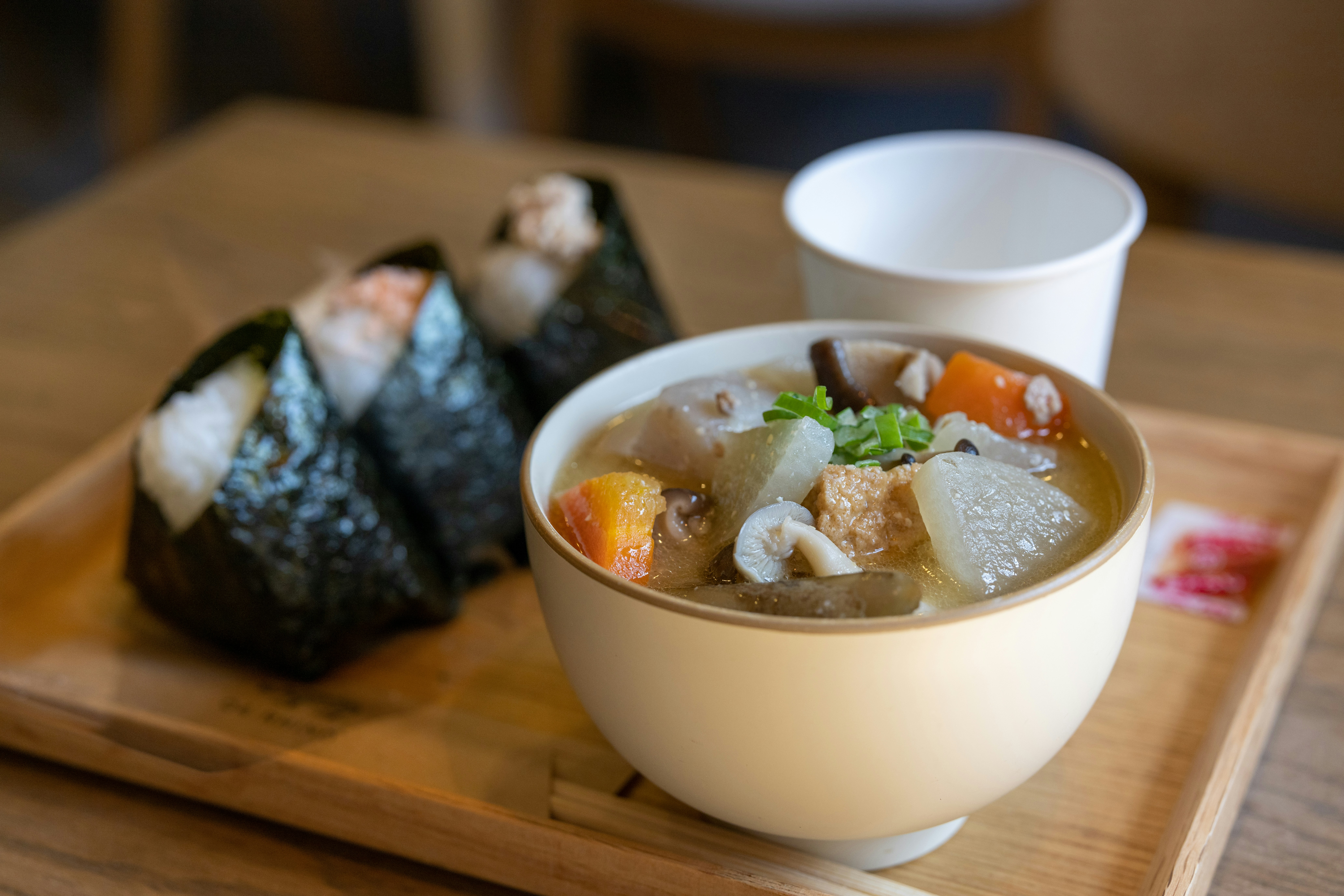 a bowl of soup and a cup of coffee on a wooden tray