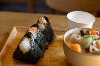 A cozy wooden table set with steaming bowls of miso soup, rice, and grilled fish, bathed in soft natural light.