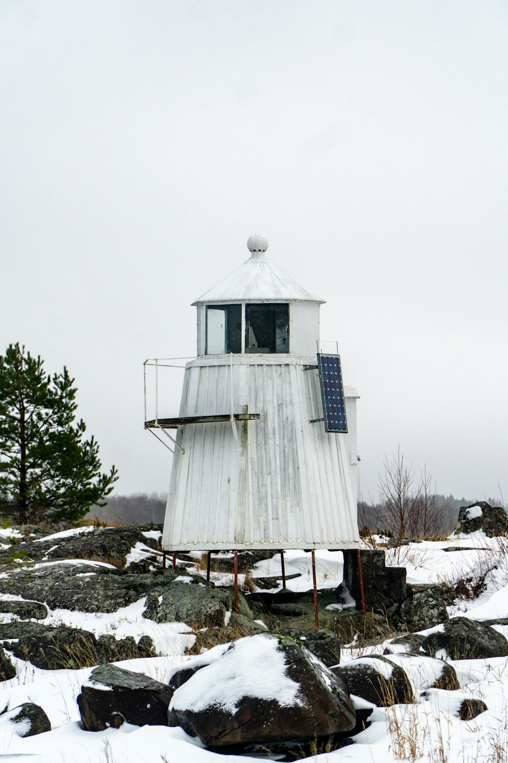 Un pequeño edificio blanco sentado en la parte superior de un campo cubierto de nieve