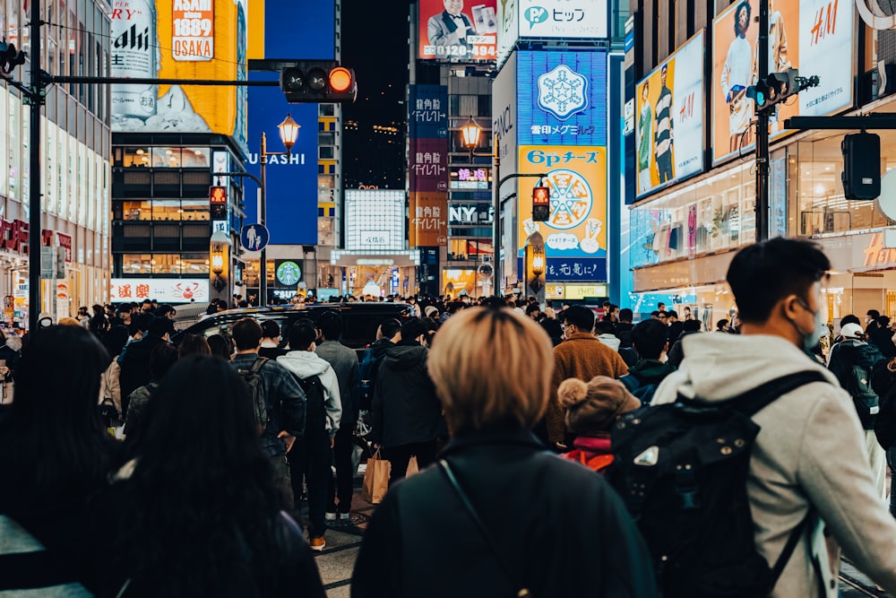 a crowd of people walking down a street next to tall buildings