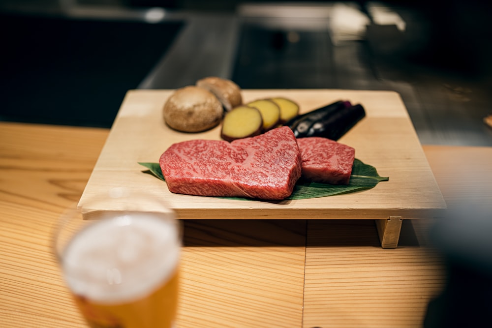 a wooden cutting board topped with meat and veggies