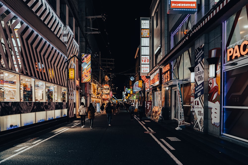 a city street at night with people walking down it