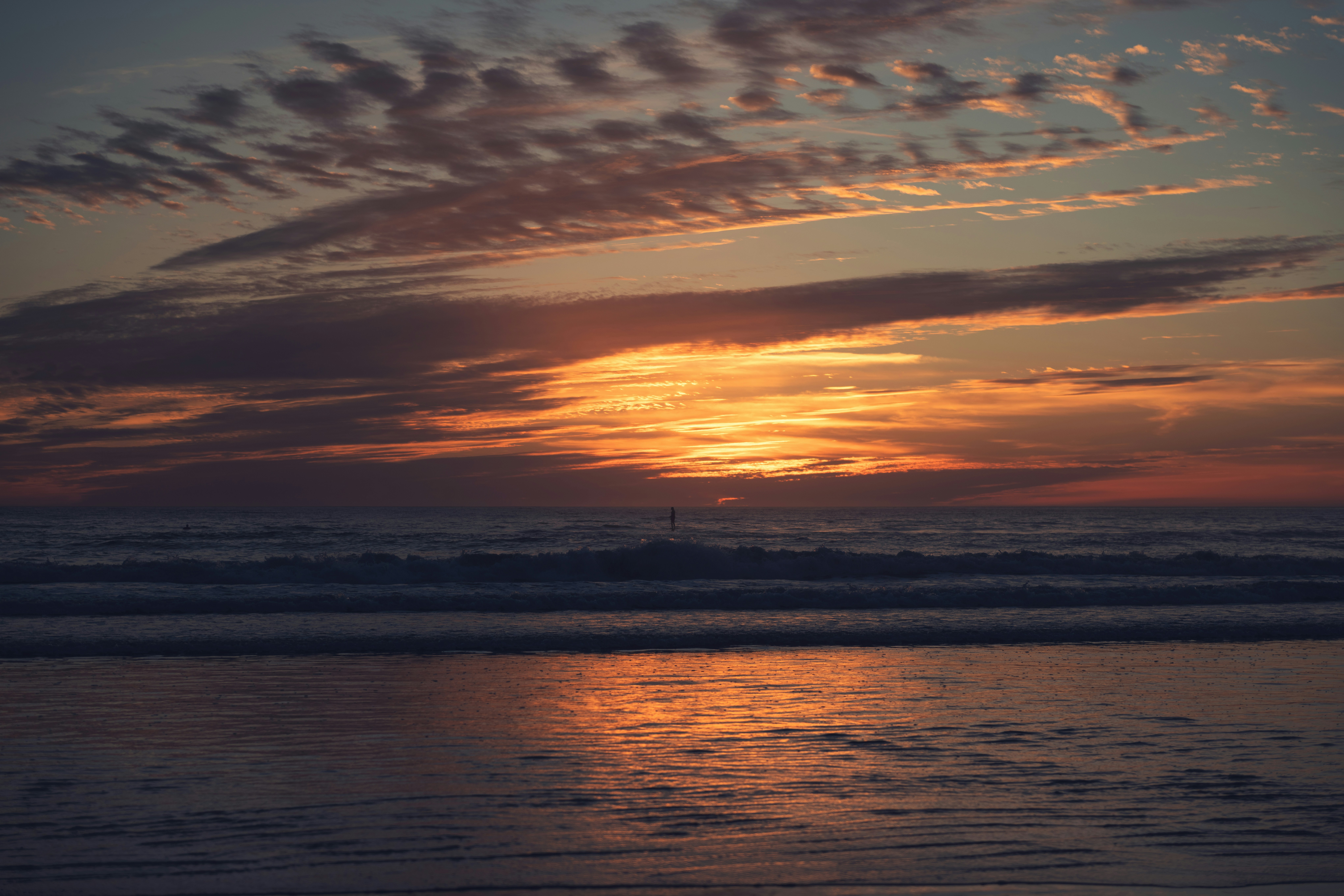 the sun is setting over the ocean on a cloudy day