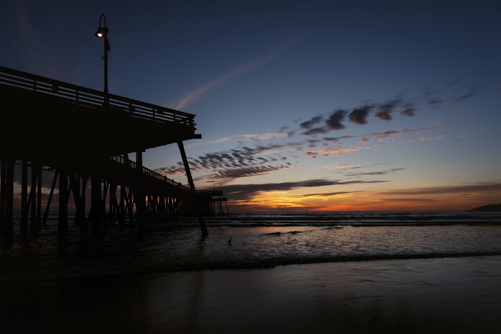 a pier at sunset with the sun going down