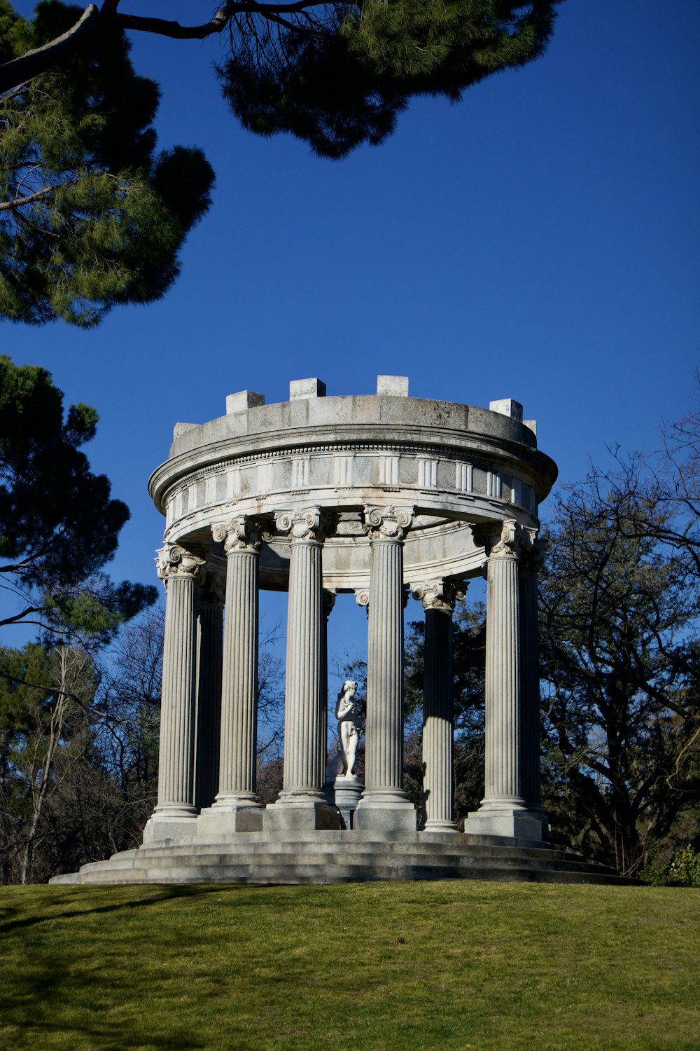 a statue of a woman standing in front of a stone structure