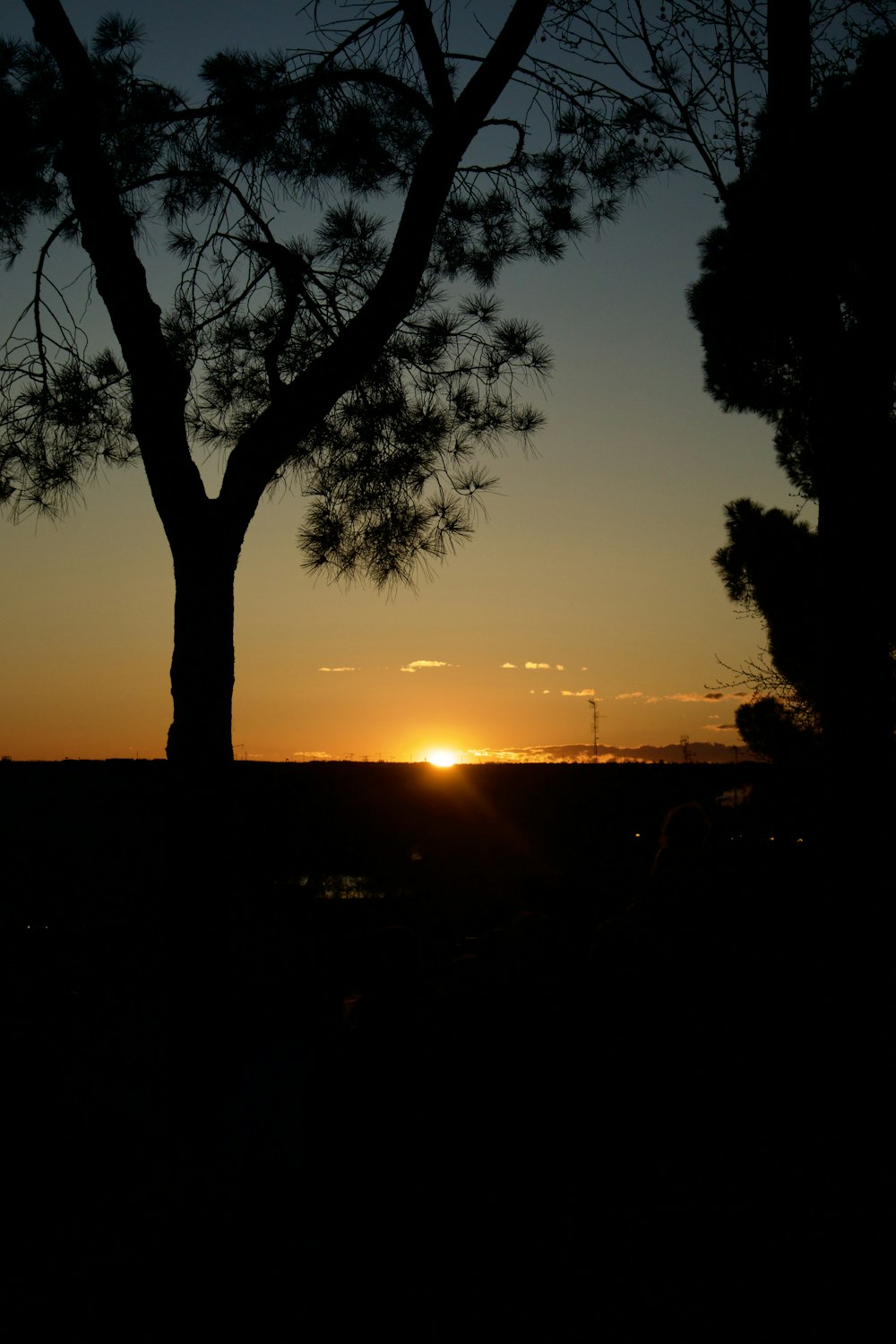 the sun is setting behind some trees