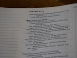 An open page of a book features text in a structured format, with headings and numbered lines. The text is focused and printed in a readable, serif font. The page number is visible at the top right corner.