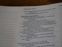 An open page of a book features text in a structured format, with headings and numbered lines. The text is focused and printed in a readable, serif font. The page number is visible at the top right corner.