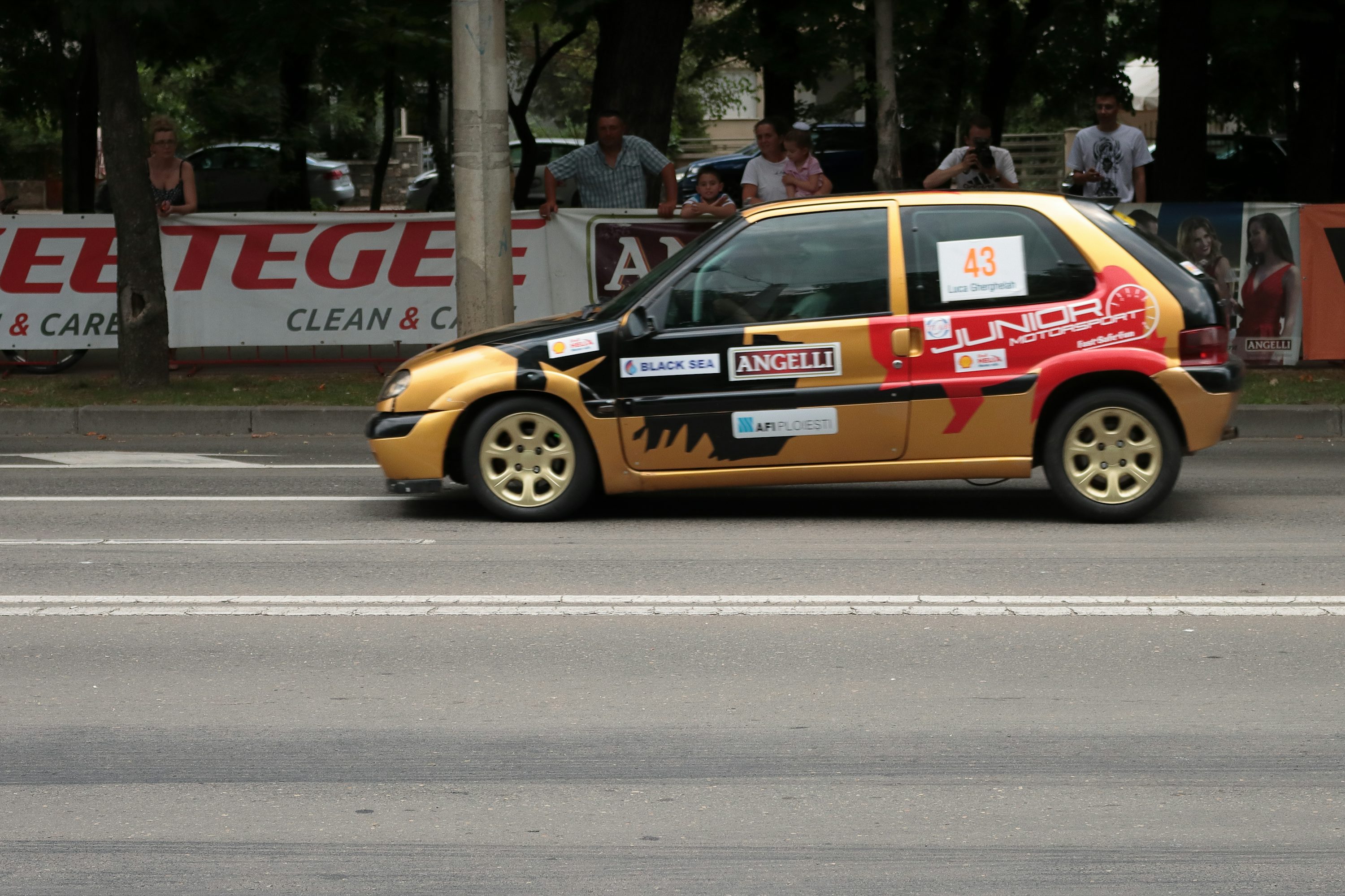 a yellow and red car driving down a street