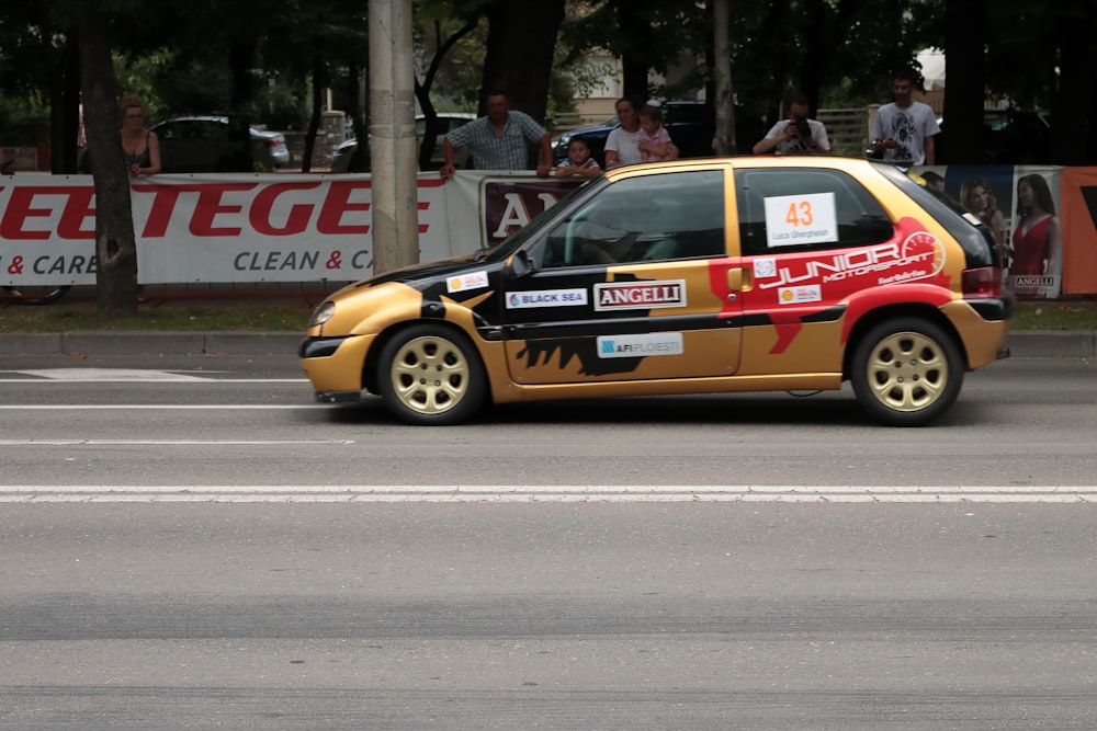 a yellow and red car driving down a street