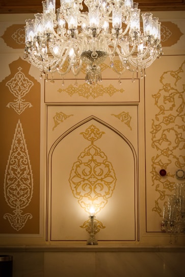 A stunning gold chandelier softly illuminating a stylish Moroccan living room with beige and white tones.