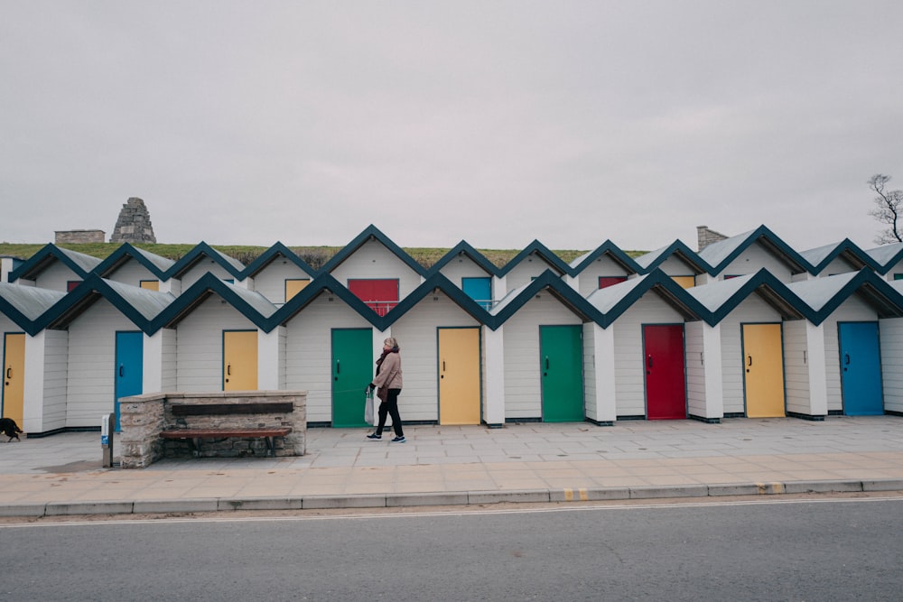 a person standing in front of a row of colorful doors